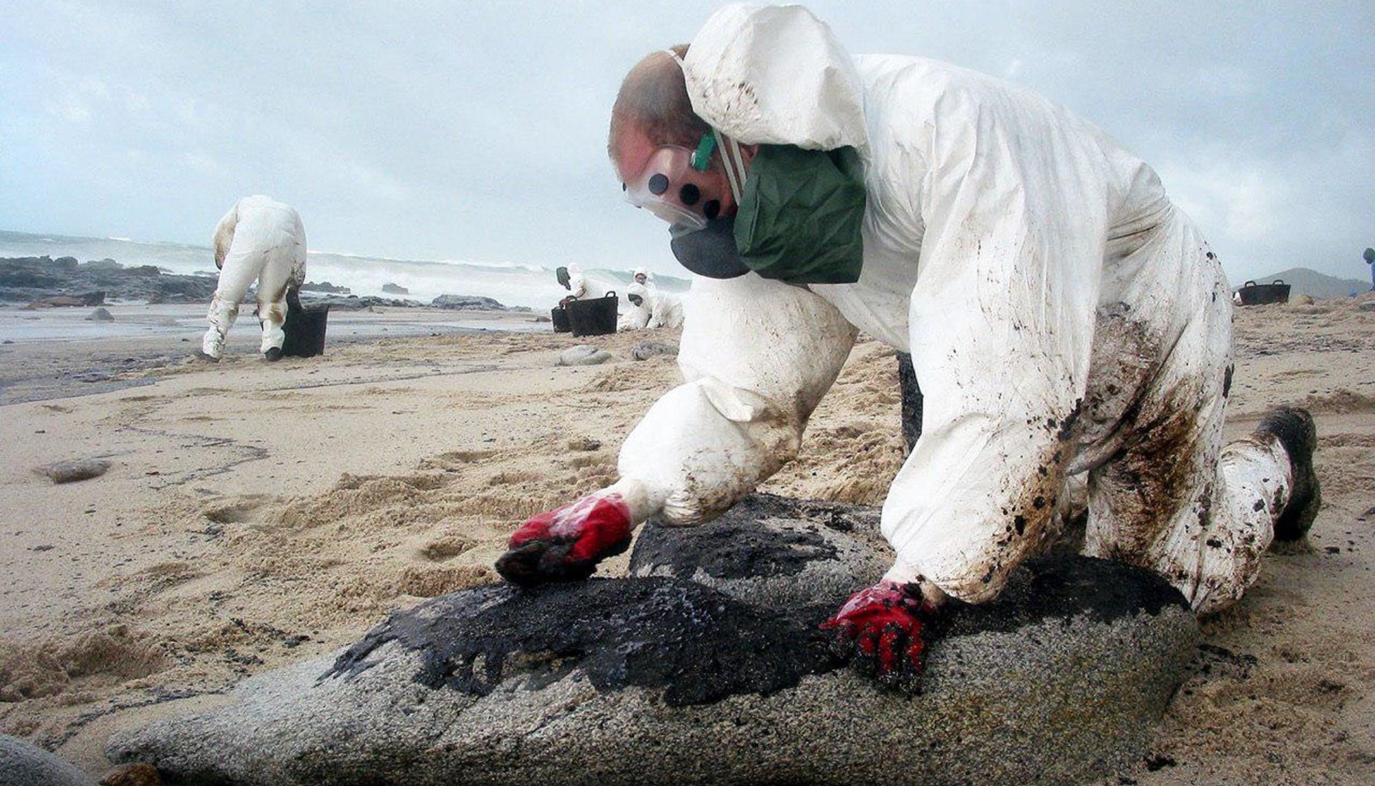 Voluntarios limpian chapapote en la costa gallega procedente del Prestige